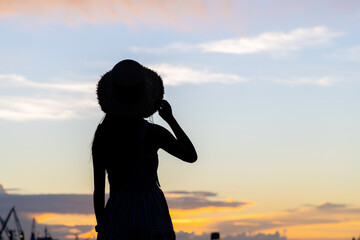 Fototapeta premium Silhouette of woman with straw hat look at the sunset view