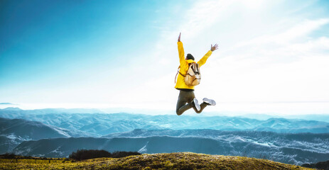 Happy man with open arms jumping on the top of mountain - Hiker with backpack celebrating success outdoor - People, success and sport concept - obrazy, fototapety, plakaty