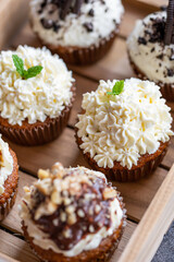 Cupcakes and muffins placed in wooden box. Chocolate and creme with nuts. Fresh home make baked sweets.