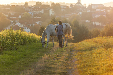 A mother and her newborn enjoying time with her horse during sundown in front of  rural farmland landscape