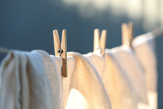 Washing line with drying shirt against blurred background, focus on clothespin
