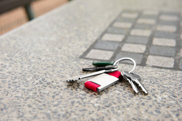 Keys forgotten on grey stone table outdoors. Space for text. Lost and found