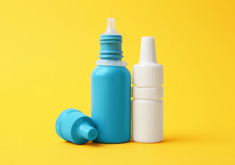 Bottles of medical drops on yellow background