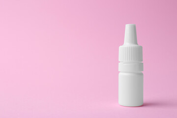 Bottle of medical drops on pink background. Space for text