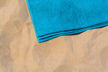 Fototapeta na wymiar Soft blue beach towel on sand, above view. Space for text