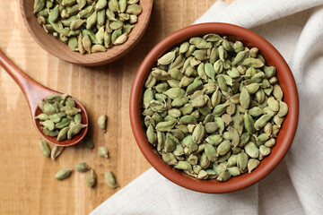 Dry cardamom pods on wooden table, flat lay
