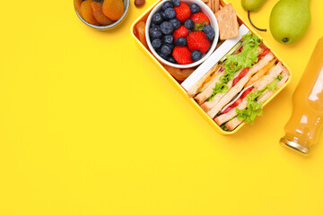 Flat lay composition with lunch box, tasty healthy food and juice on yellow background, space for...