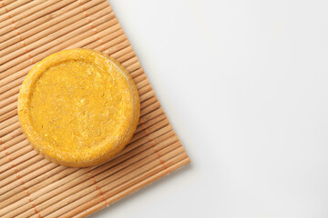 Yellow solid shampoo bar on light table, top view. Space for text