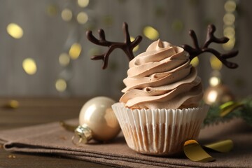 Tasty Christmas cupcake with chocolate reindeer antlers on wooden table, closeup. Space for text