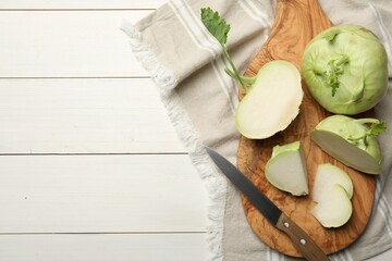 Whole and cut kohlrabi plants on white wooden table, flat lay. Space for text