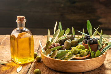 olives berries in wood bowls and pressed oil in glass bottles on a wooden background. place for text