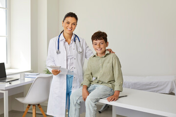 Happy, smiling doctor and child at a modern clinic or hospital. Portrait of a pediatrician standing...