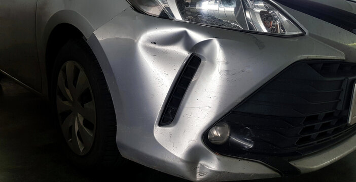 Scratches or dents on gray, grey or bronze car after accident. Damaged on injured on front bumper.