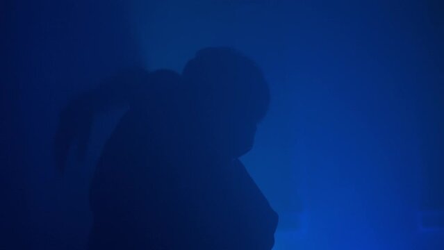 Silhouette Of Man In Creepy Mask Dancing In Spotlights And Smoke At Carnival Party. Person Wearing Plague Doctor Hanging Out At Freak Style Disco