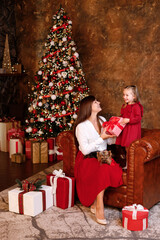 cute girl and mom near the christmas tree with gifts.