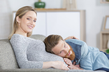 Obraz na płótnie Canvas man rests his head on wifes pregnant tummy