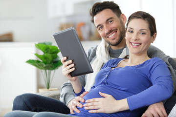 cheerful couple using digital tablet at home