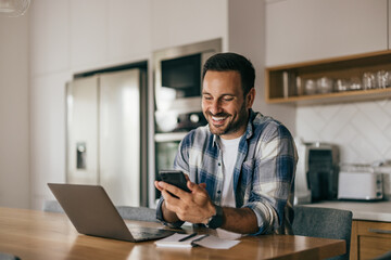 Obraz na płótnie Canvas Smiling businessman using a phone while working at home.