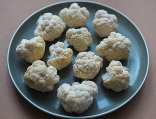 Cauliflower on a plate close-up view from above. Raw cauliflower close-up in a plate.  Broccoli in...
