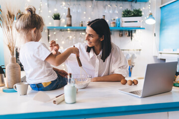 Smiling woman having fun with daughter at kitchen counter