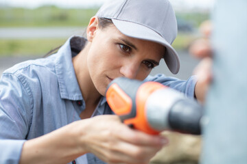 serious builder woman using electric screwdriver