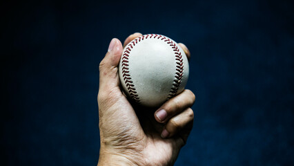 Selective focus of man holding baseball ball isolated on black background.