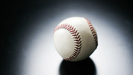 White leather baseball poses on black background.