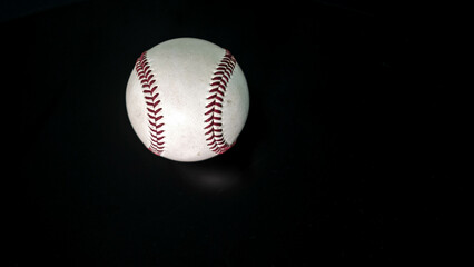 White leather baseball poses on black background.