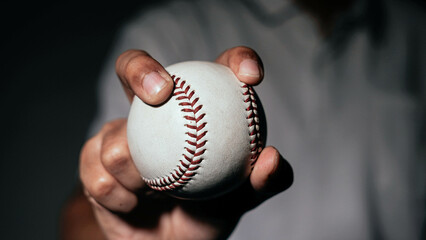 Selective focus of man holding baseball ball isolated on black background.