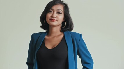 Tilt down shot of Asian woman wearing classic blue suit posing for camera at studio while shooting new clothing collection for lookbook