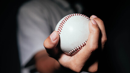 Selective focus of man holding baseball ball isolated on black background.