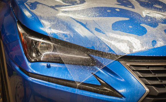 The process of installing PPF on the hood of the car.PPF is a protective film for paint that protects the paint from scratches and gravel.Anti-gravity protection. PFF is installed. Car wrapping. 