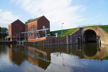 Fototapeta premium Coastal pumping station near the small harbor at the Ley Bay in Greetsiel, western East Frisia, Lower Saxony, Germany, Europe.