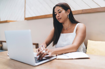 Ethnic woman working on laptop at table in cafe