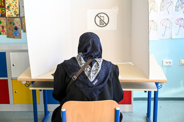 Muslim woman with scarf voting on elections. Voters on election day.  People go to the polls. Presidential and parliamentary elections.  - obrazy, fototapety, plakaty