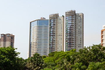 Alguns prédios residenciais com várias bandeiras brasileiras nas janelas vistos entre árvores de...