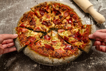 Young people sharing slices of innovative pizza baked with gray dough. Healthy eating, homemade Italian cuisine.