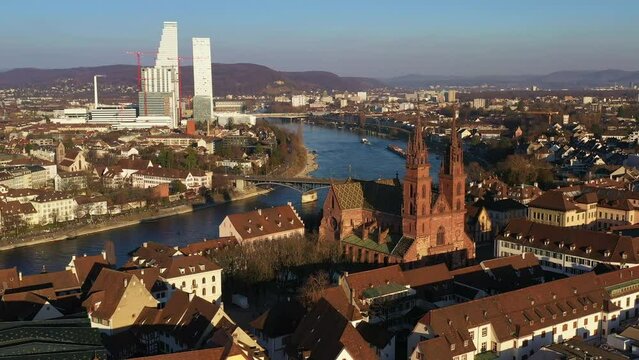 Basel, Switzerland: Aerial drone footage of the Basel cathedral, the Basler Munster, with modern office towers in the background along the Rhine river in Switzerland. 