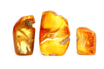 Amber with patterns on a white background. Three pieces of yellow sun stone. Jewelry material. Natural semi-precious mineral. Ancient fossil resin. Copal. Geology and science. landscape mineral