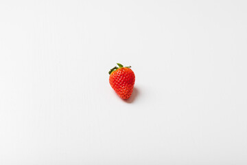 Red strawberry with a green stem is isolated on a white background.
