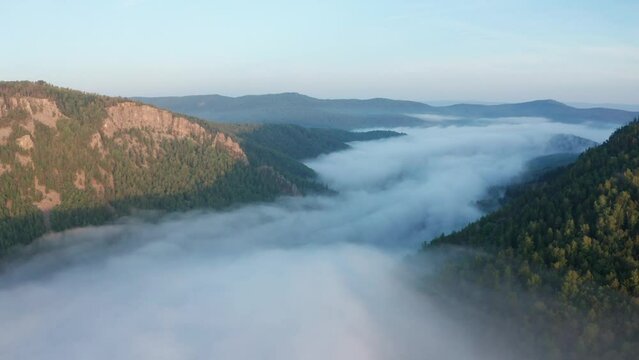 Flying over mountain valley filled by clouds. Nature of Ural region of Russia