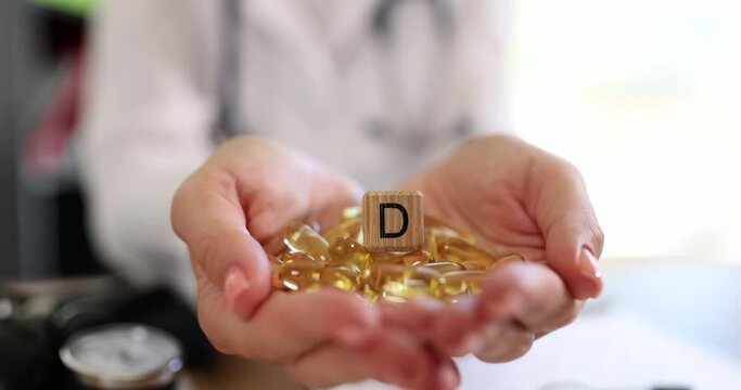 The yellow capsules of vitamin D in the palms of the doctor