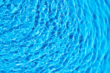 Blue water texture background, water surface with sun rays reflection, high resolution.