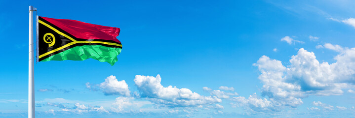 Vanuatu flag waving on a blue sky in beautiful clouds - Horizontal banner