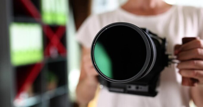 Shiny glass of the camera lens in the hands of a woman