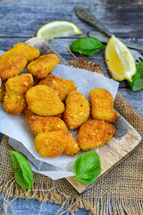 
 Crispy oven baked  chicken Nuggets  with garlic sauce.Breaded chicken fillets  with chilly peppers and fresh basil on wooden rustic background