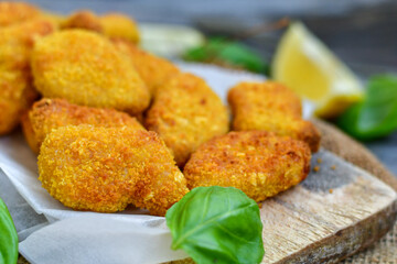 
 Crispy oven baked  chicken Nuggets  with garlic sauce.Breaded chicken fillets  with chilly peppers and fresh basil on wooden rustic background