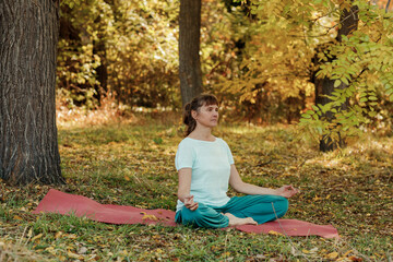 An elderly woman practices yoga in the autumn forest