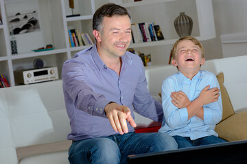 Obraz premium dad and his son watching a comedy