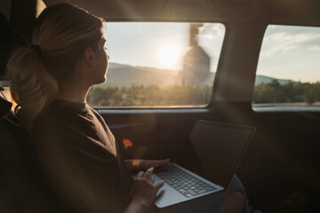 woman working from her laptop while traveling in daylight in a private vehicle,private transportation and daylight